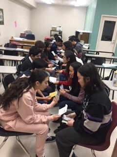 Picture of students sitting in chairs looking at one another
