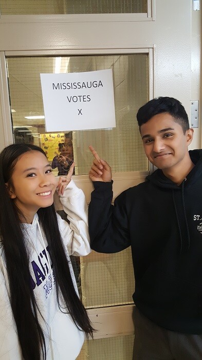 Two students pointing at a sign